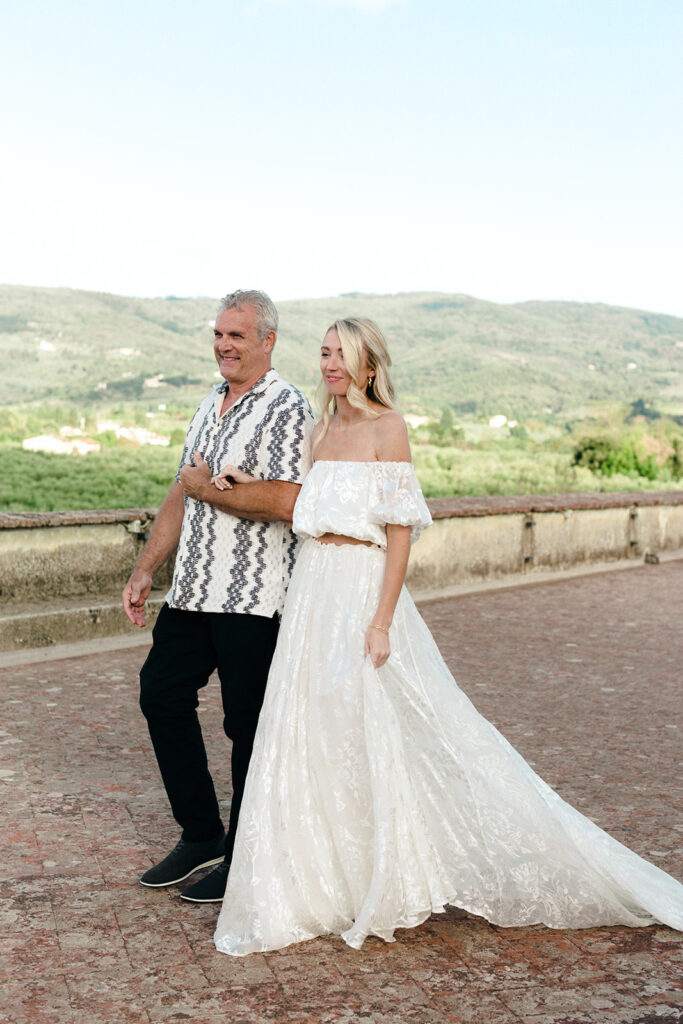 Bride and father walking into venue for rehearsal dinner in italy 