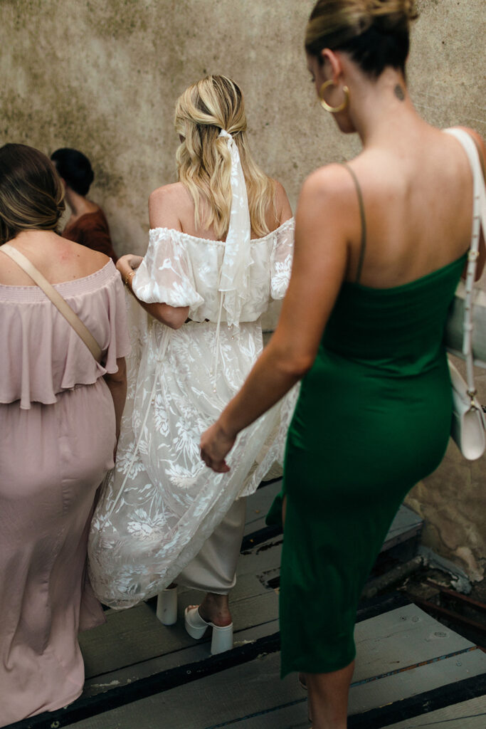Bride walking out of rehearsal dinner with help of bridesmaids 